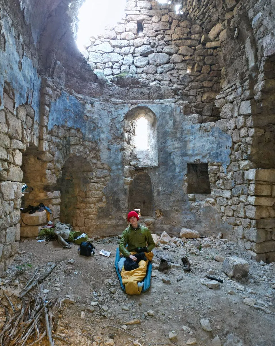 Inside Nuka Sakdari: blue plaster on the apse, the stone roof open to the sky, and the camp laid out on the ground.