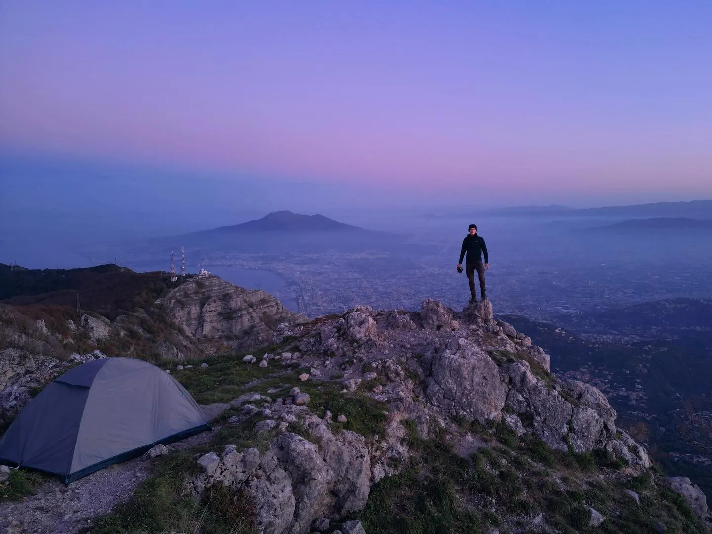 A small tent pitched on the rocky summit of Monte Molare at dawn, Tassilo on the crag above a sea of pink mist, the Bay of Naples and Vesuvius on the horizon