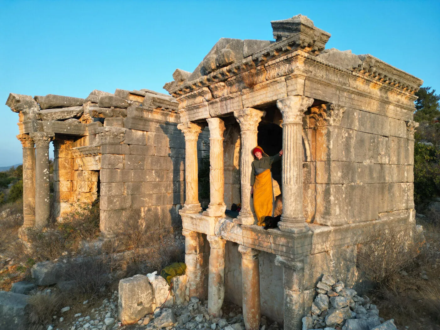 An intact Roman tomb-temple with columns and a small figure inside in golden light